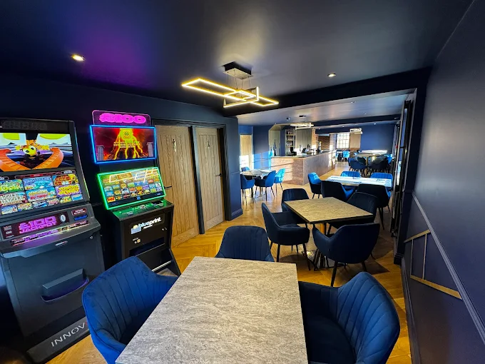The Queen's Head Kingsnorth pub toilets at back with slot game machines and tables with pub bar in the background